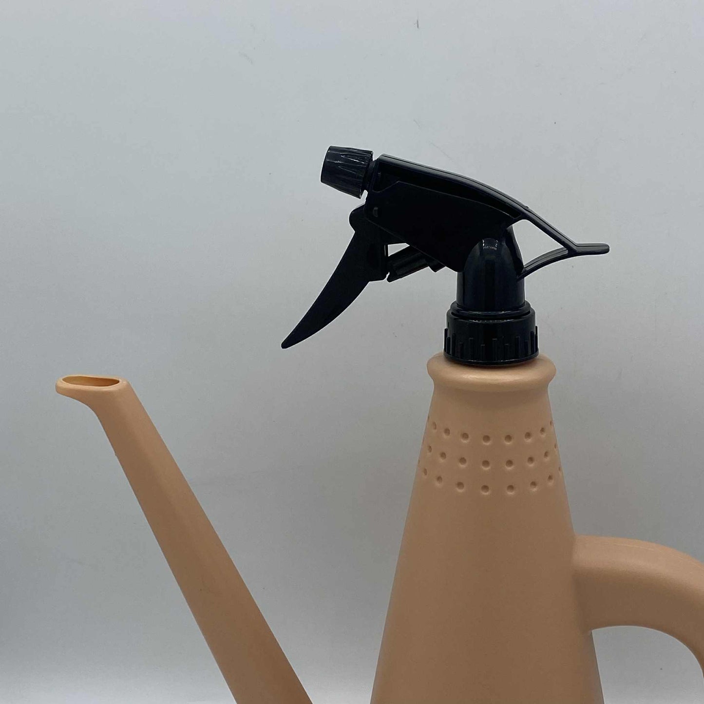 Un arrosoir en plastique beige avec une buse classique et un pulvérisateur à gâchette noir sur le dessus.