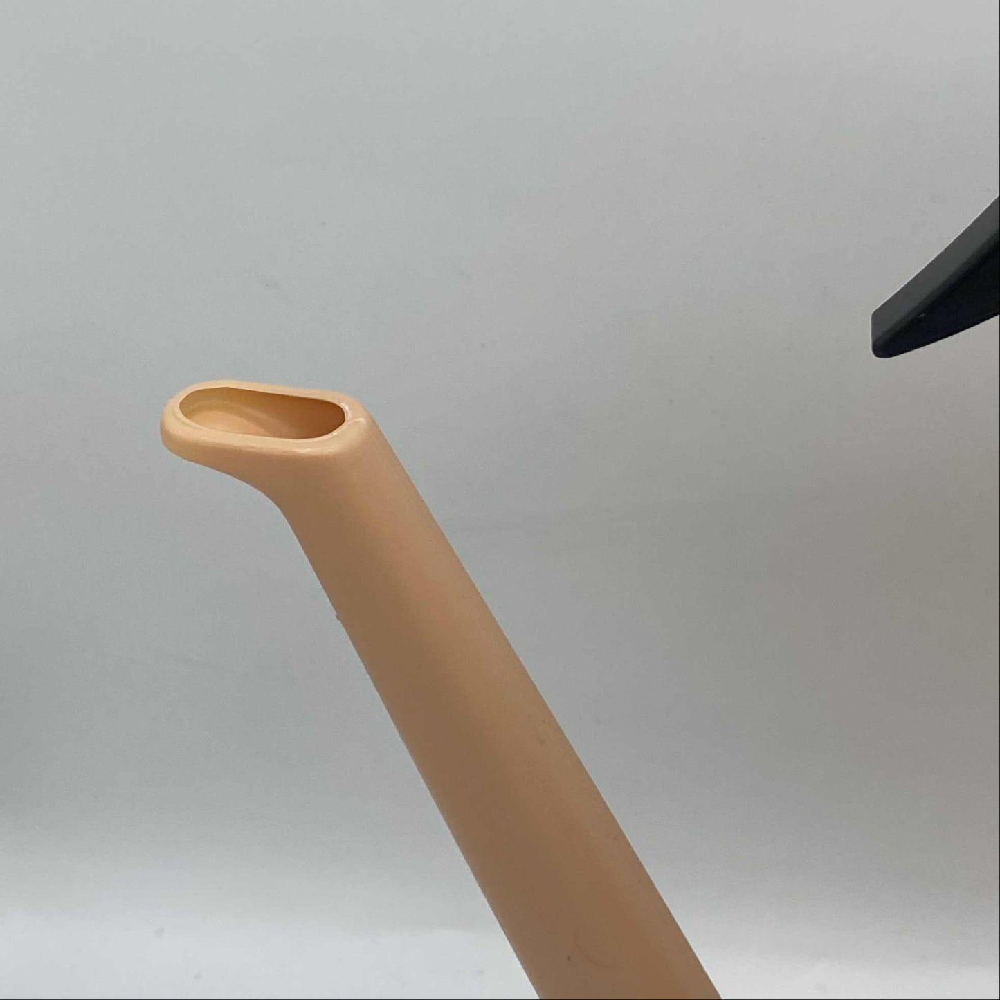 Gros plan sur le bec rectangulaire d'un arrosoir en plastique beige, montrant un arrosoir hybride.