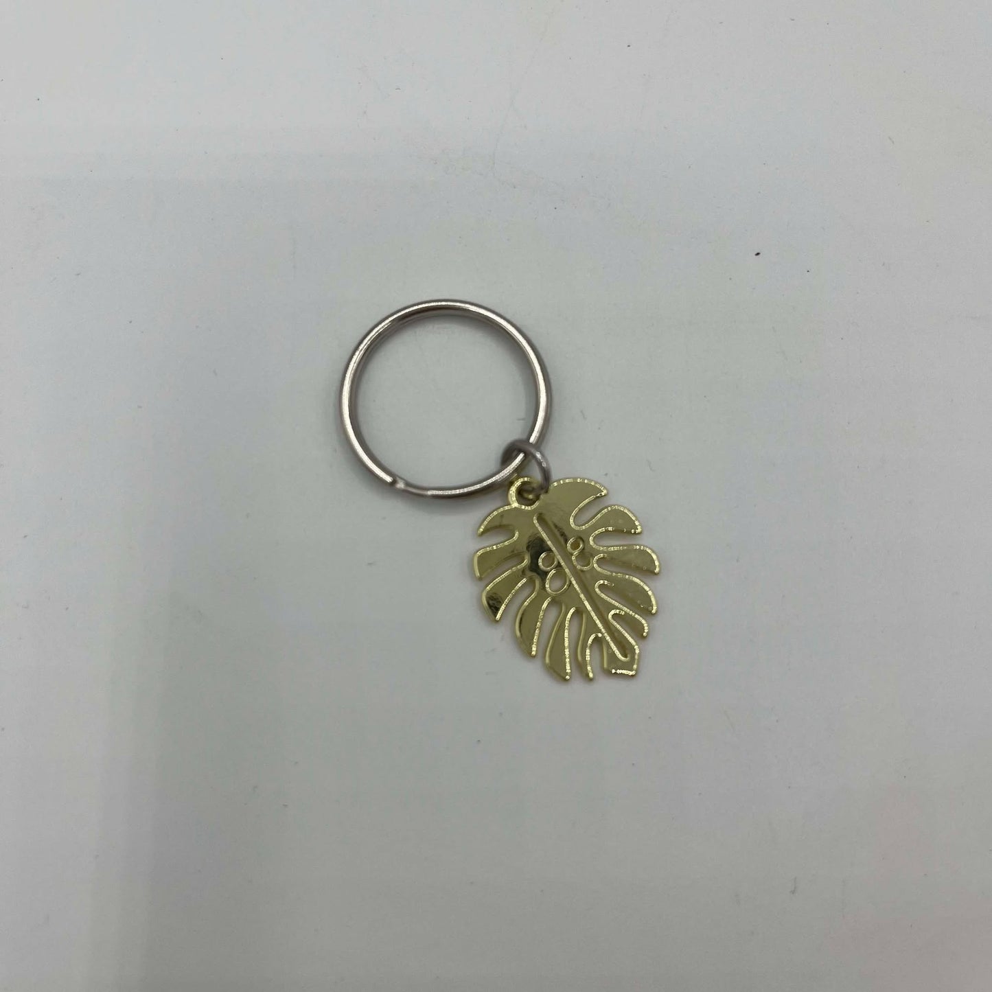 mini porte clé monstera couleur or sur un fond blanc