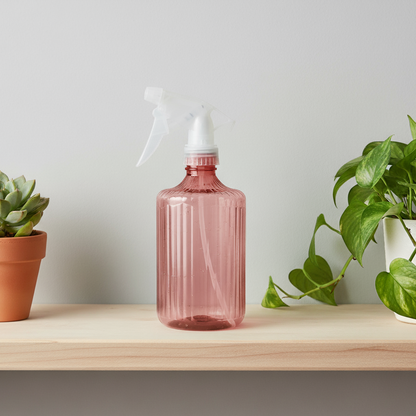 Flacon pulvérisateur rose/ambre sur tablette en bois rustique avec des plantes grasses.