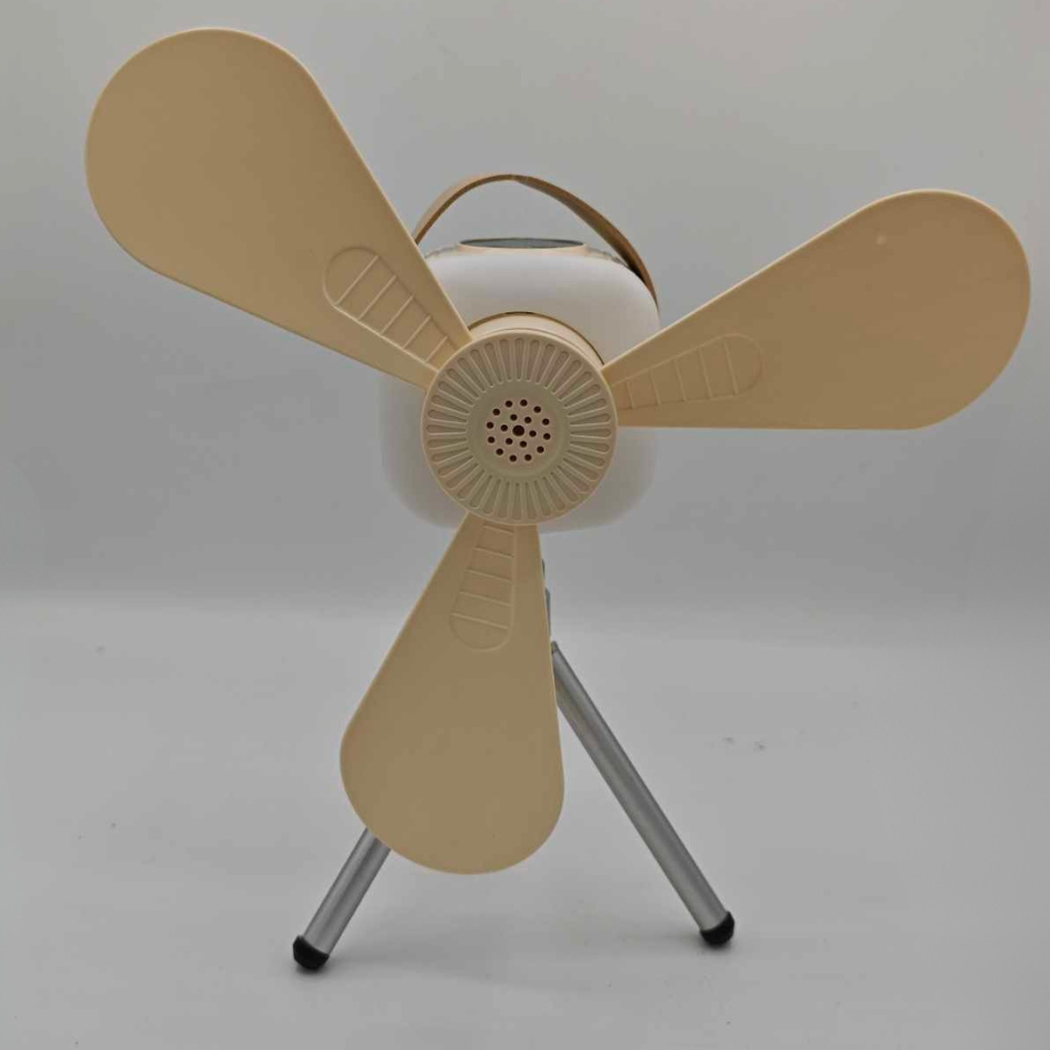 Ventilateur anti-moustiques portable de couleur crème, posé sur un trépied en aluminium. Le ventilateur a trois pales, une grille centrale, et une poignée de transport en cuir sur le dessus. Le fond est blanc et uni.