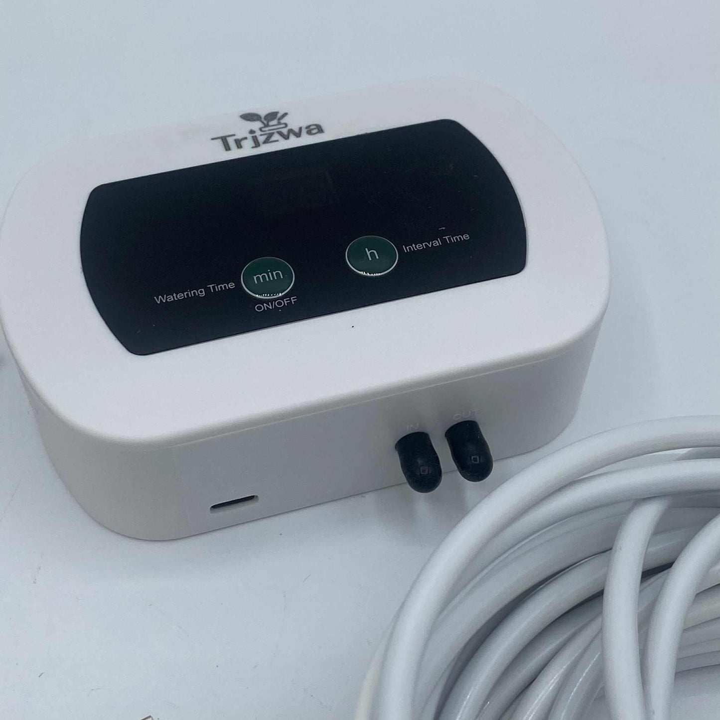 Gros plan sur le boîtier de commande blanc d'un système d'arrosage automatique, avec des boutons pour régler le temps d'arrosage et l'intervalle.