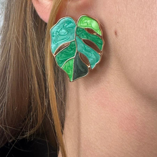 boucle d'oreille en forme de monstera porté par une fille à son oreille droite