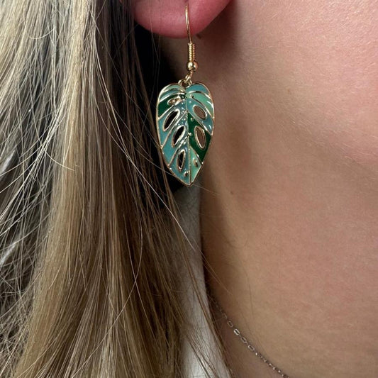 boucle d'oreille monstera couleur portée par une fille sur son oreille droite