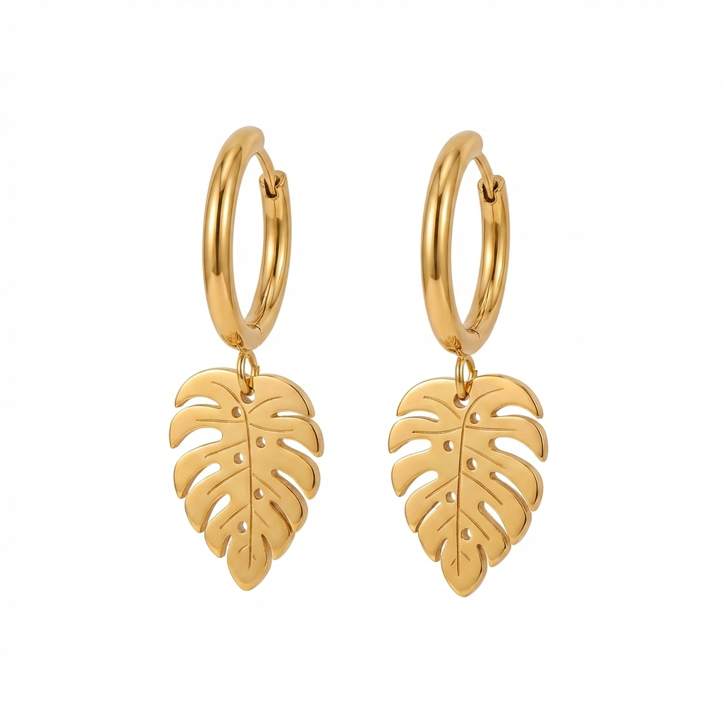 Paire de boucles d'oreilles créoles dorées avec un pendentif en forme de feuille de monstera. Vue de face sur fond blanc uni, fermoir charnière visible.
