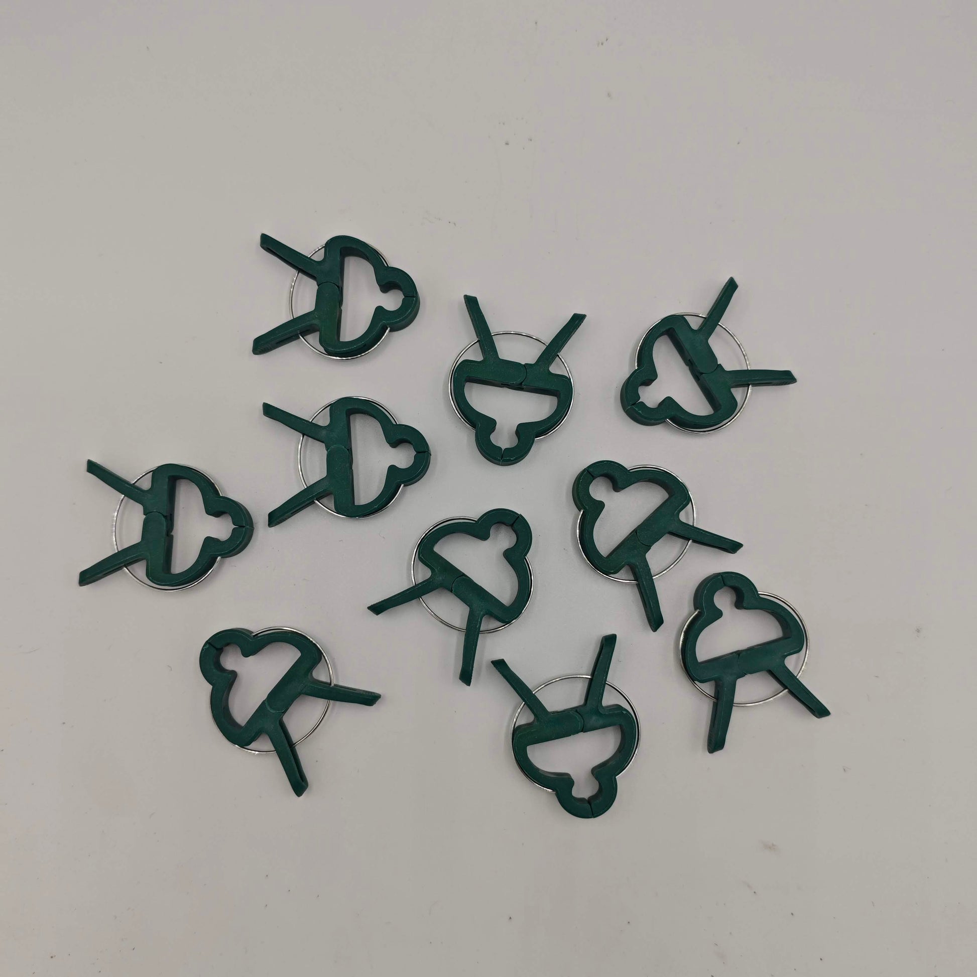 Un lot de dix clips de support pour plantes en plastique vert, avec un design en forme de papillon et un ressort métallique.