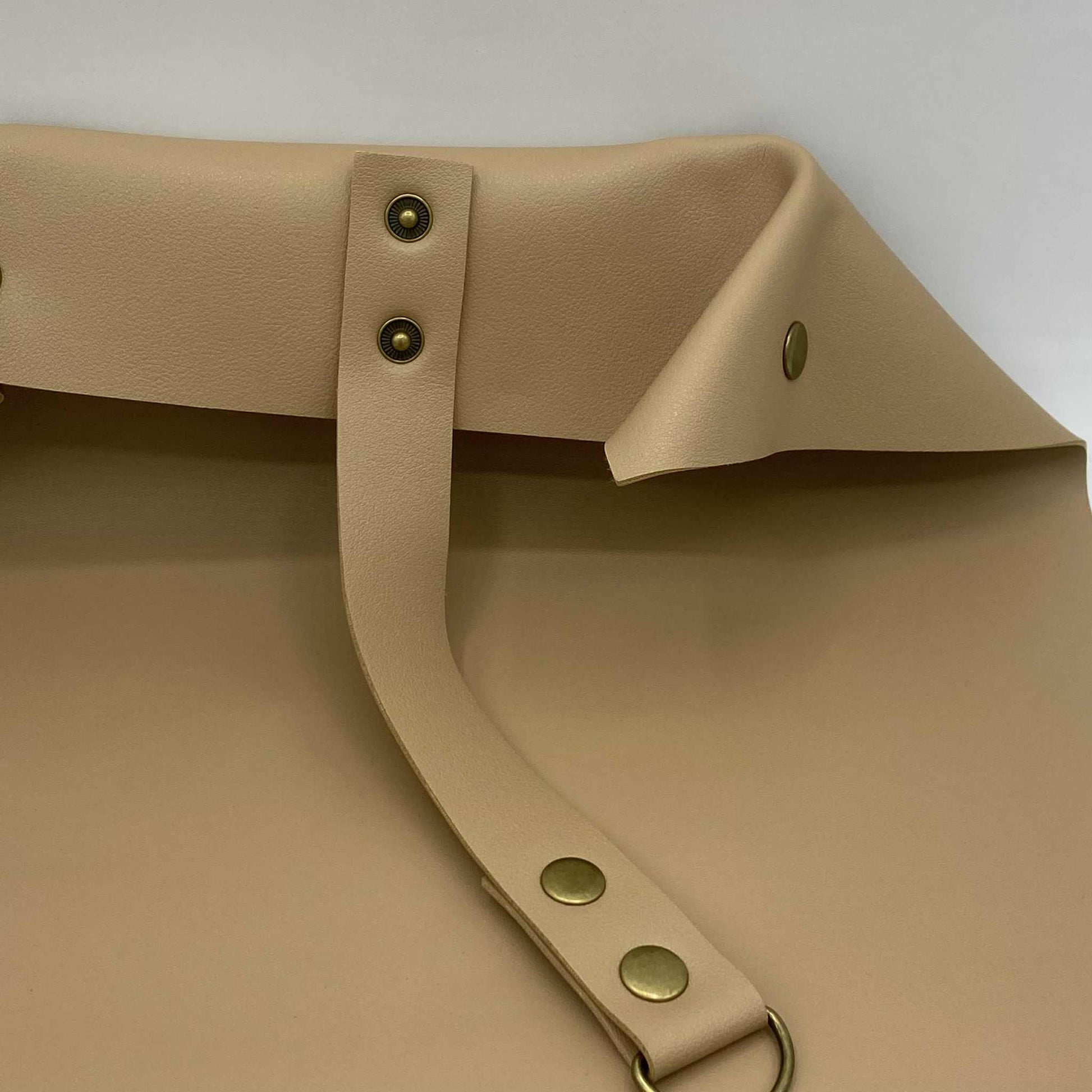 Gros plan sur le système de fermeture d'un tapis de rempotage beige, avec les boutons-pression et la sangle.