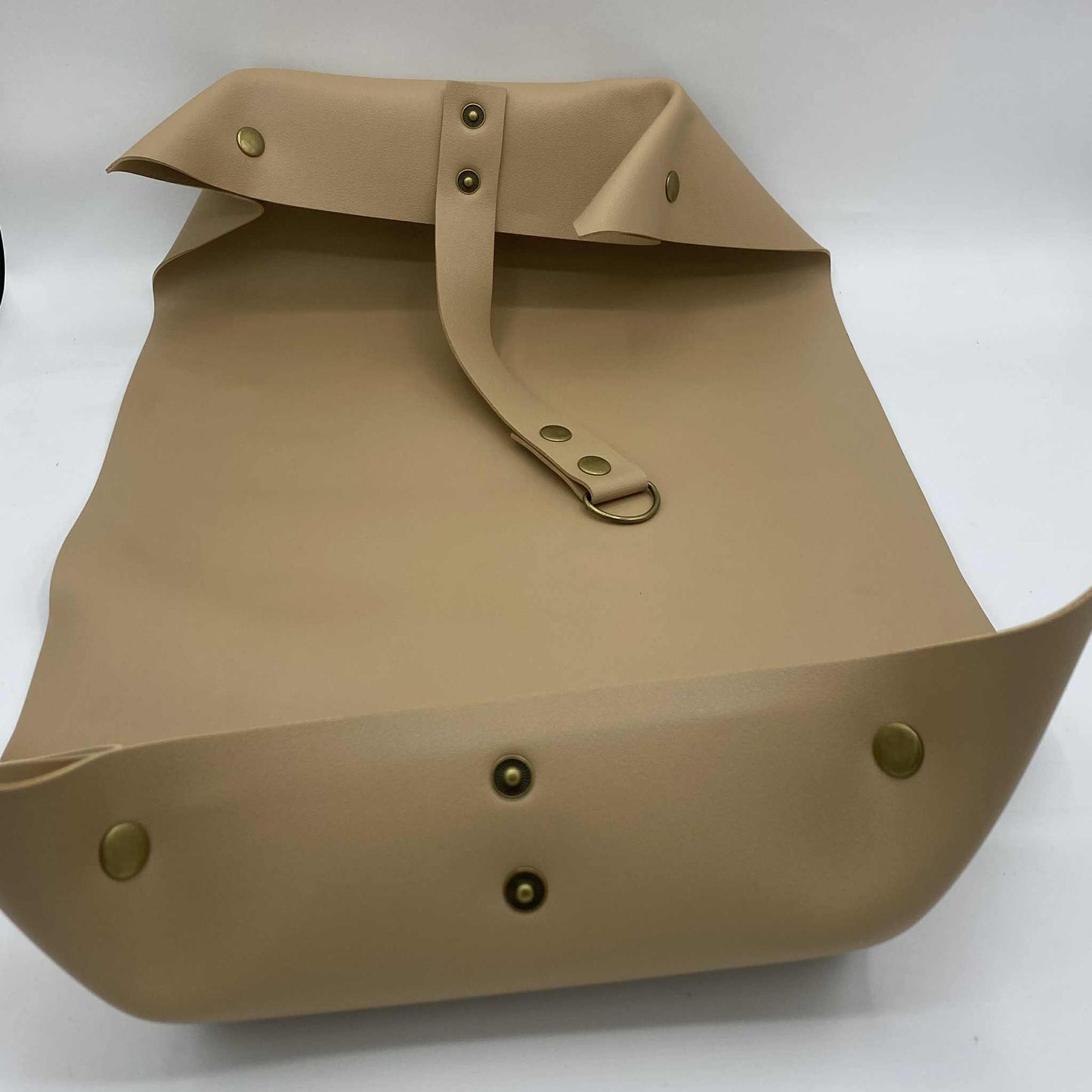 Un tapis de rempotage beige, avec les boutons-pression et la sangle visibles, montrant sa capacité à se transformer en plateau.
