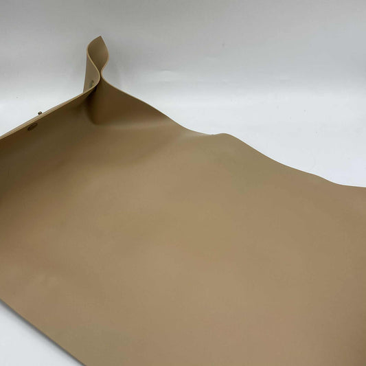 Gros plan sur un coin relevé d'un tapis de rempotage beige, montrant le bouton-pression qui crée une barrière anti-salissures.